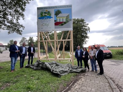 Vertreter von Politik und Verwaltung stehen vor dem Bauschild