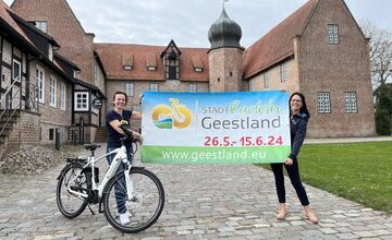 Dana Hebener und Sonja Thomas mit STADTRADELN-Plakat vor der Burg Bederkesa