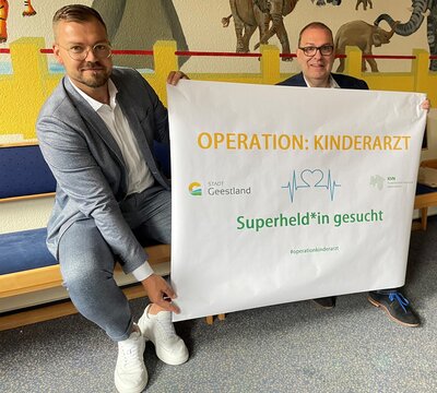 KVN-Geschäftsführer Sören Rievers (links) und Geestlands Bürgermeister Thorsten Krüger halten ein Banner in die Kamera