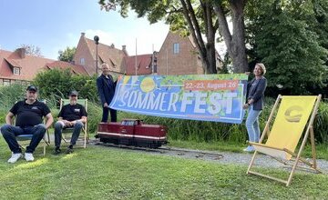 Vertreter der Stadt Geestland, vom Verschönerungsverein und von der Museuumsbahn mit Banner für Sommerfest vor der Burg Bederkesa