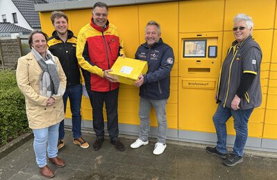 Vertreter von Stadt und Post stehen vor der neuen Poststation in Debstedt