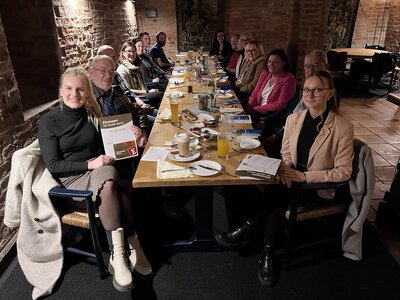 Ehrenamtliche sitzen gemeinsam an einem Tisch im Kellergewölbe der Burg Bederkesa