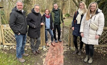 Veranstalter stehen vor einer offenen Gartenpforte