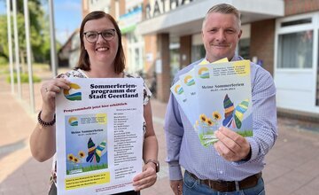 Mareike Buck und Dennis Rösner von der Stadt Geestland halten das neue Programmheft in den Händen