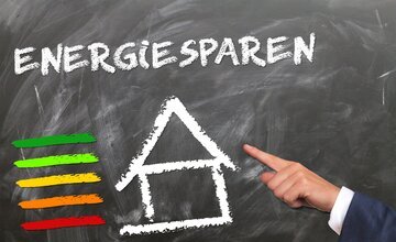 Finger zeigt auf Haus, darüber die Aufschrift: Energie sparen