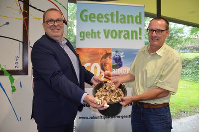 Bürgermeister Krüger und Projektleiter Ullrich zeigen einen Eimer Hackschnitzel