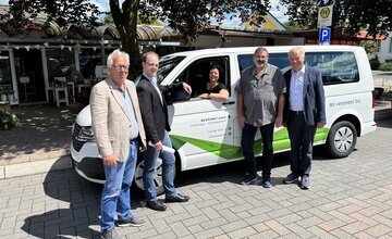 Vertreter von Verwaltung und Busunternehmen vor einem VW-Bus am Neumarkt