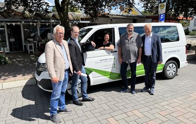 Vertreter von Verwaltung und Busunternehmen vor einem VW-Bus am Neumarkt