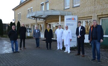 Vertreter von Ameos und der Stadt Geestland stehen vor dem Ameos-Klinikum Debstedt
