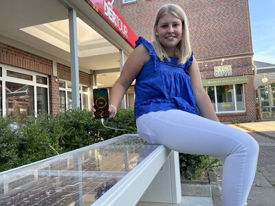 Auszubildende Leonie Näth sitzt auf der neuen Solarbank im Lindenhof